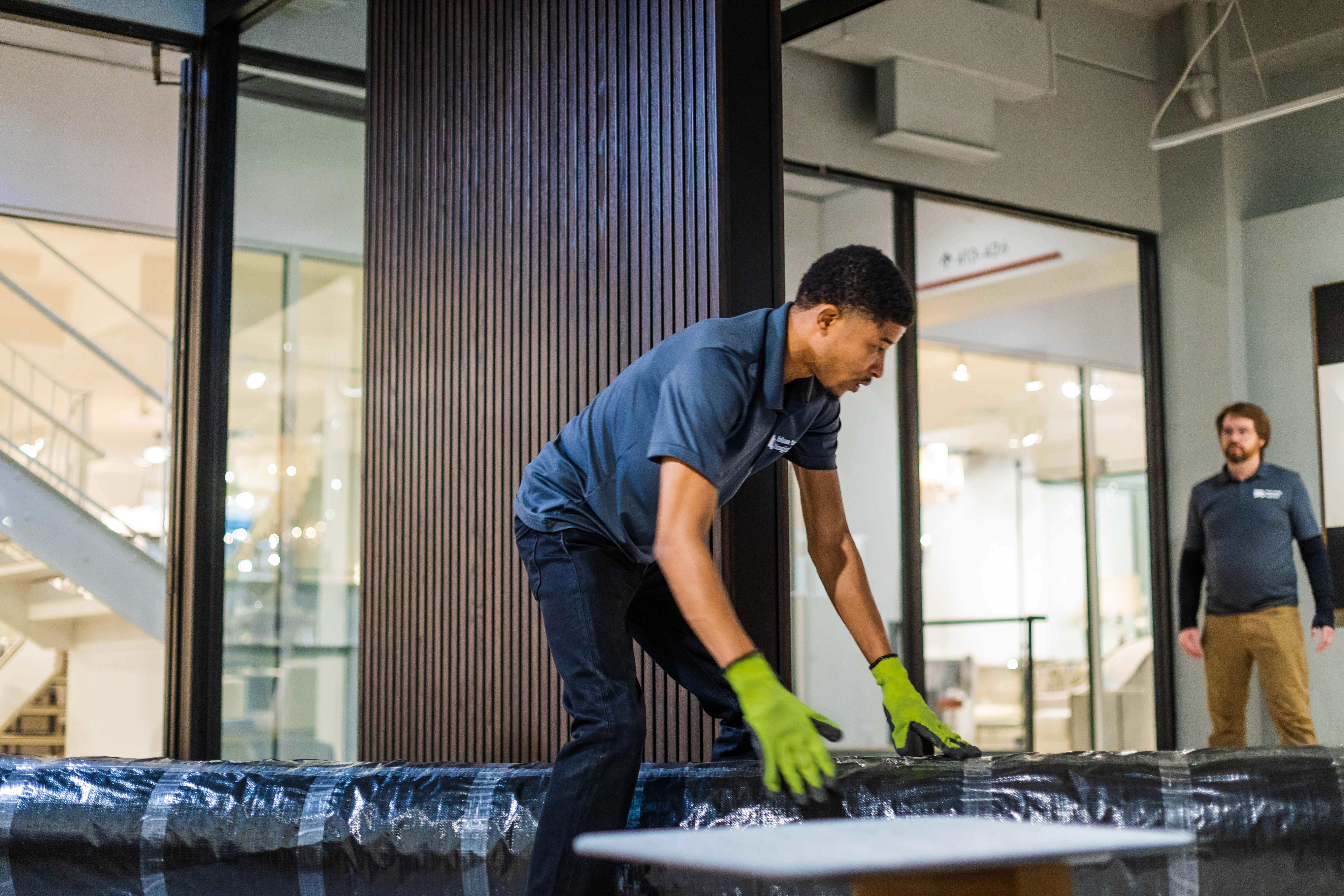 A skilled mover prepares to handle a large rug in an upscale environment