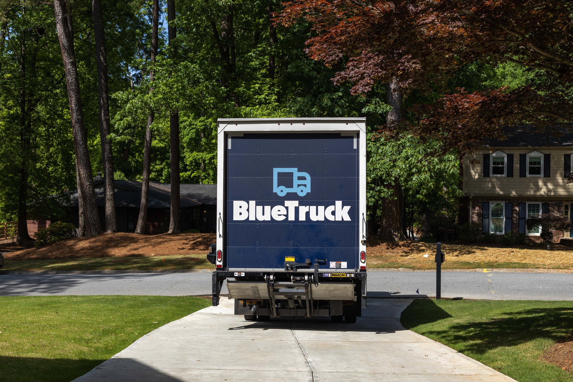 Blue Truck residential furniture delivery truck backing up to customer house